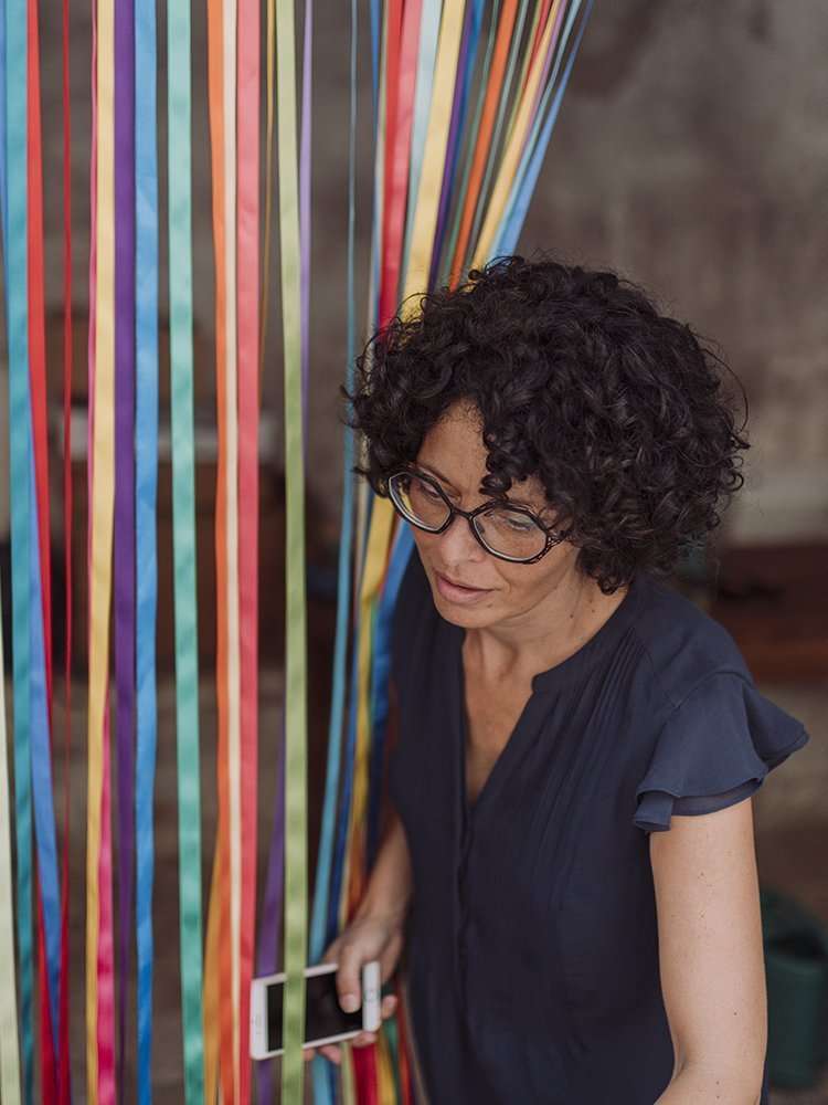 Organizzatore di matrimoni Maria Mayer durante i preparativi del matrimonio estivo a colori attorniata da tantissimi nastri colorati che scendono sul tavolo