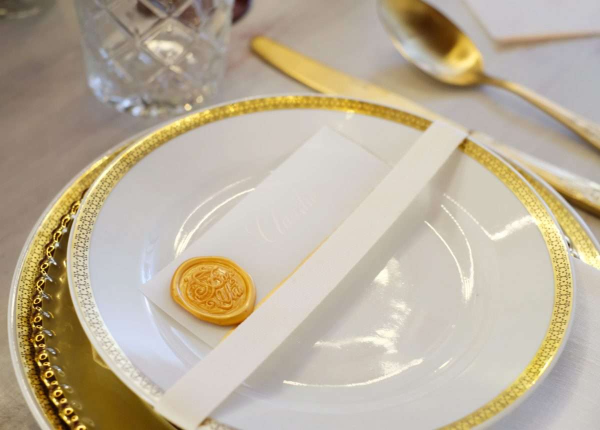 wedding planner Maria Mayer primo piano di piatto in porcellana bianca con decori dorati e posate dorate