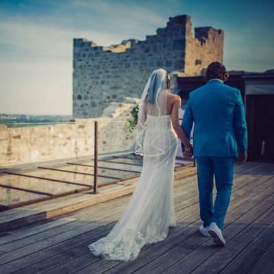 Foto di sposi nella location del loro matrimonio presi di spalle, lui in abito blu, lei in abito bianco